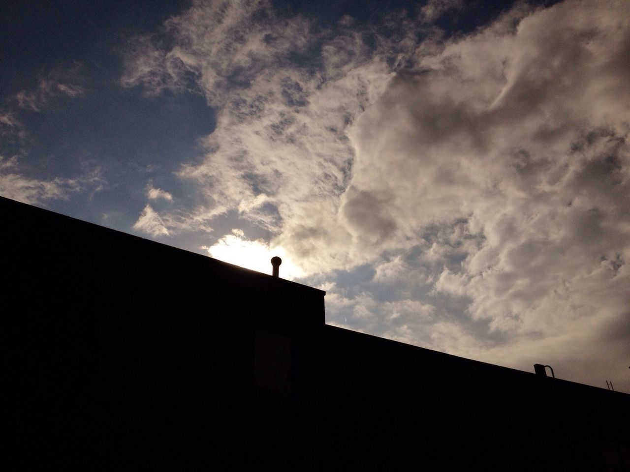 Silhouette building against cloudy sky