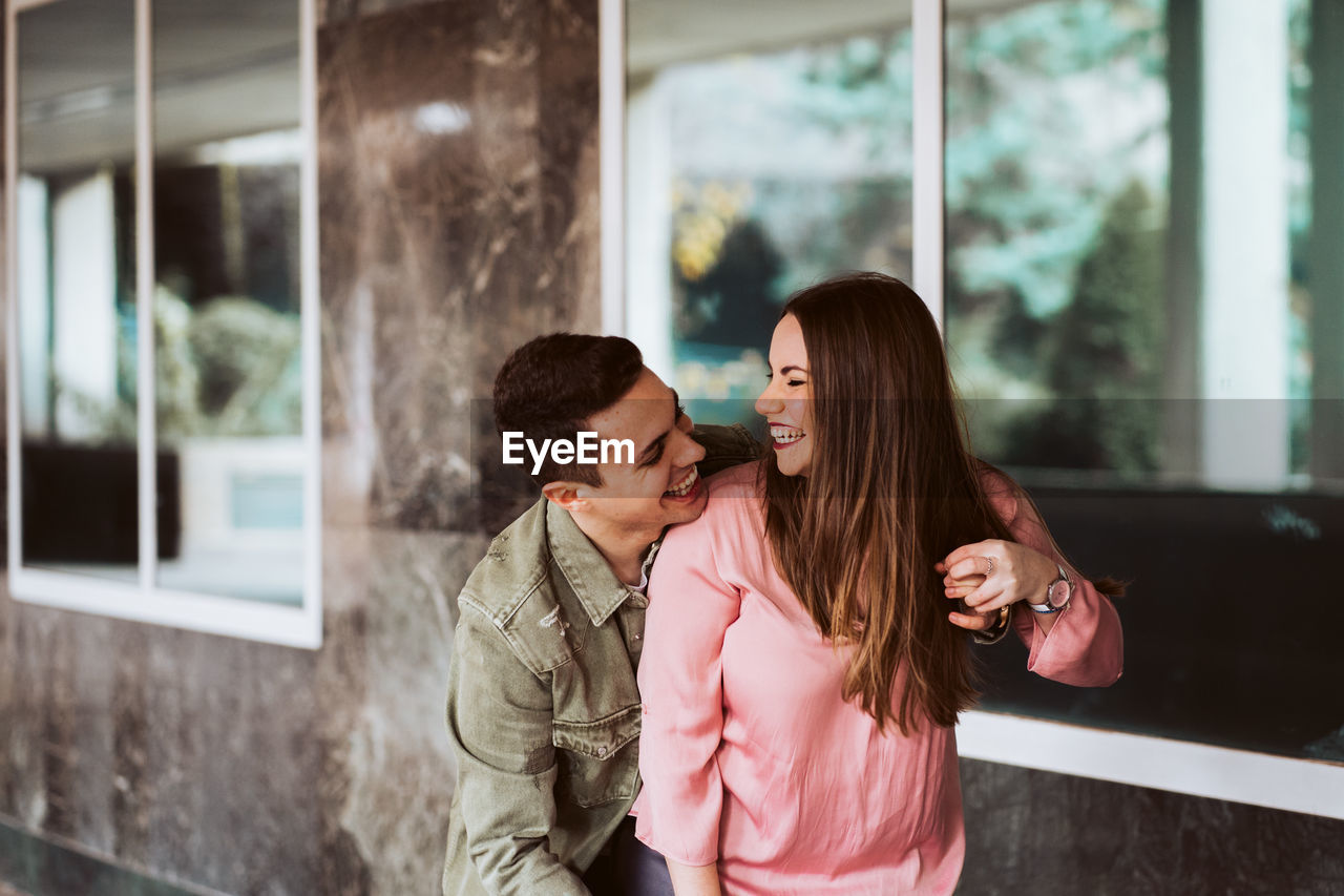 Young couple embracing against window