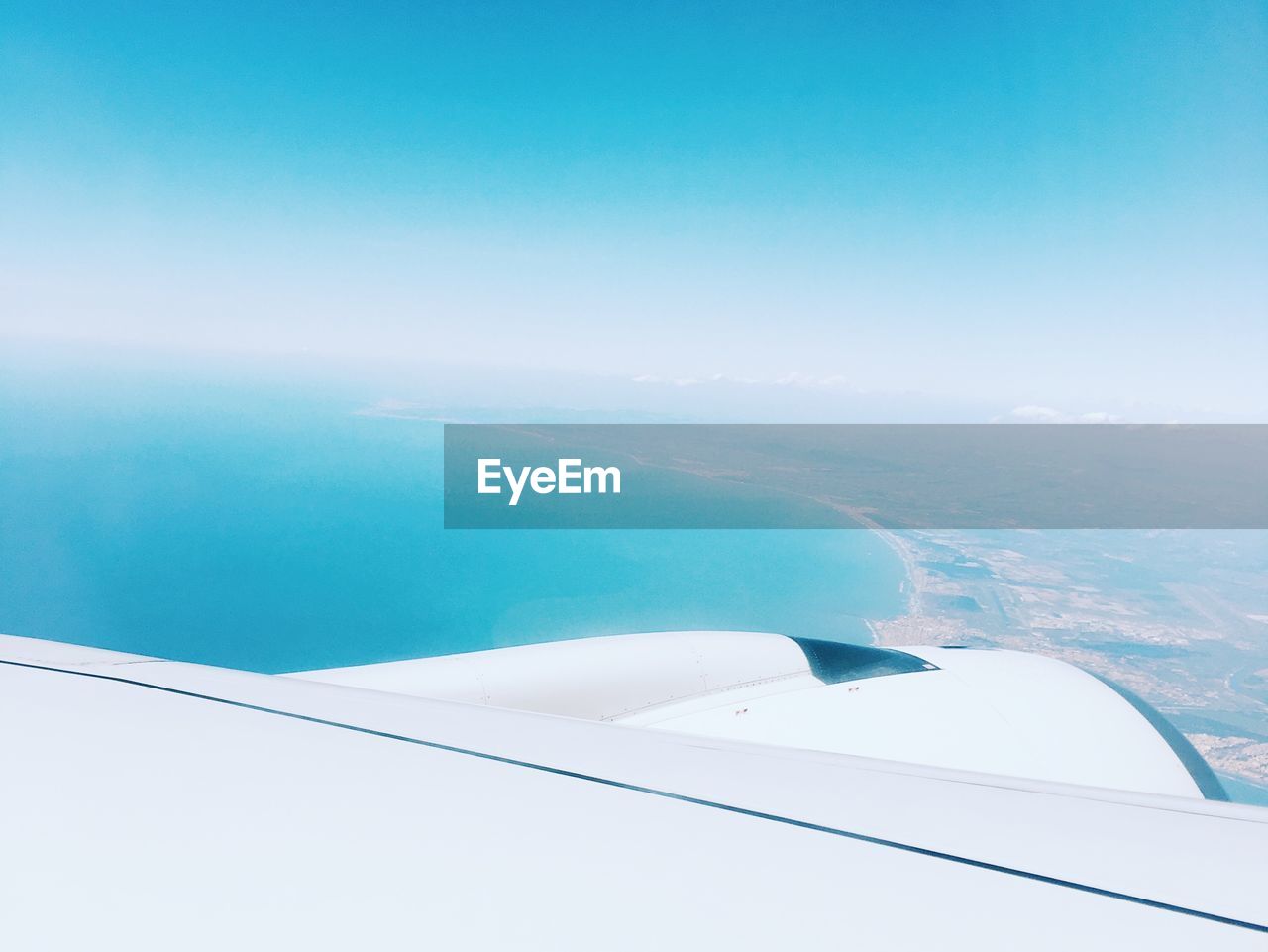 Cropped image of airplane flying over sea against blue sky