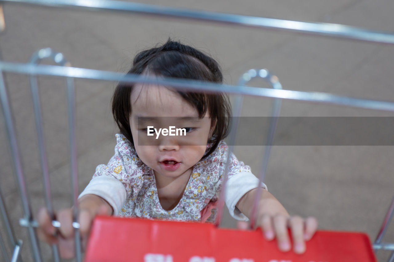 Cute baby girl touching shopping cart