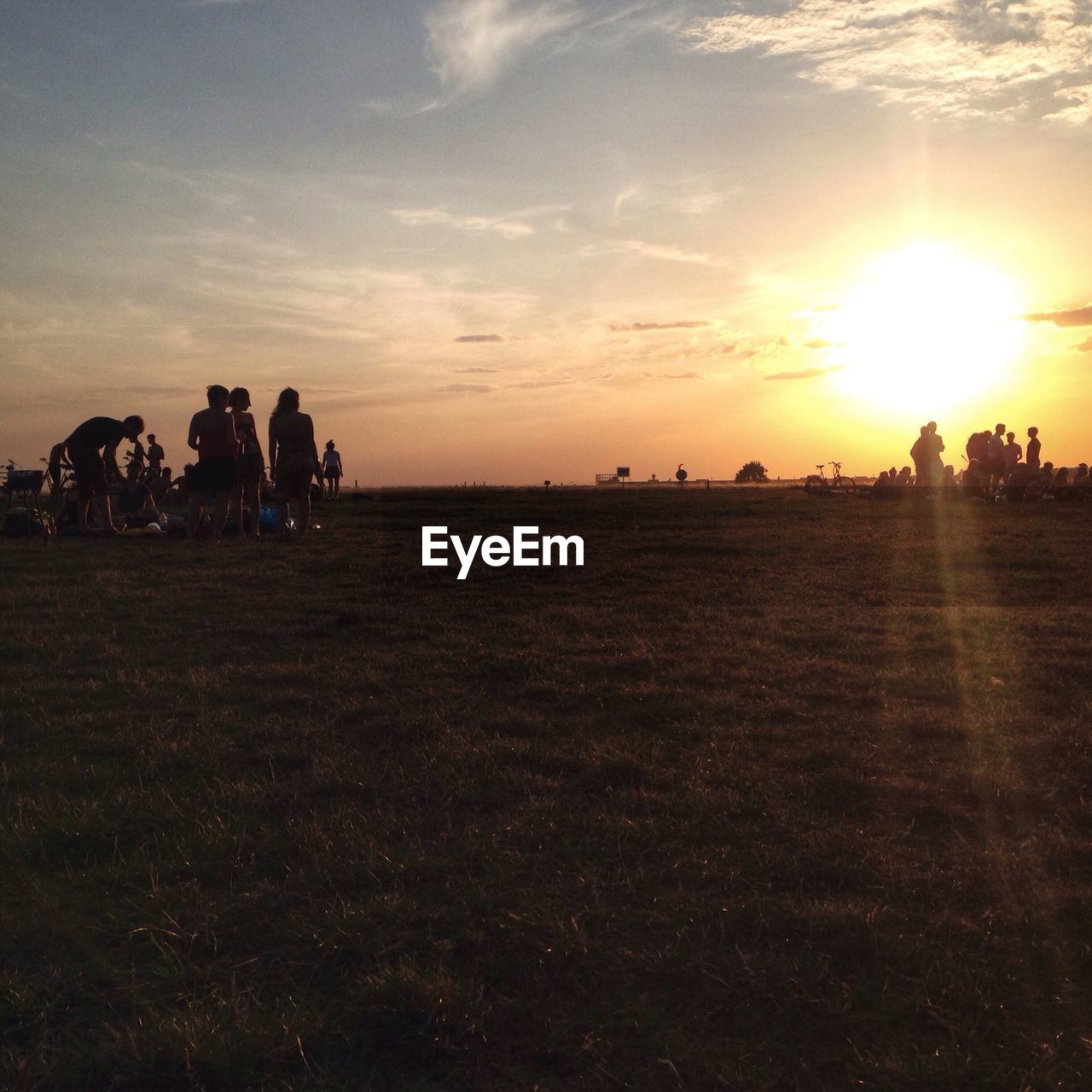 People on grassy field during sunset