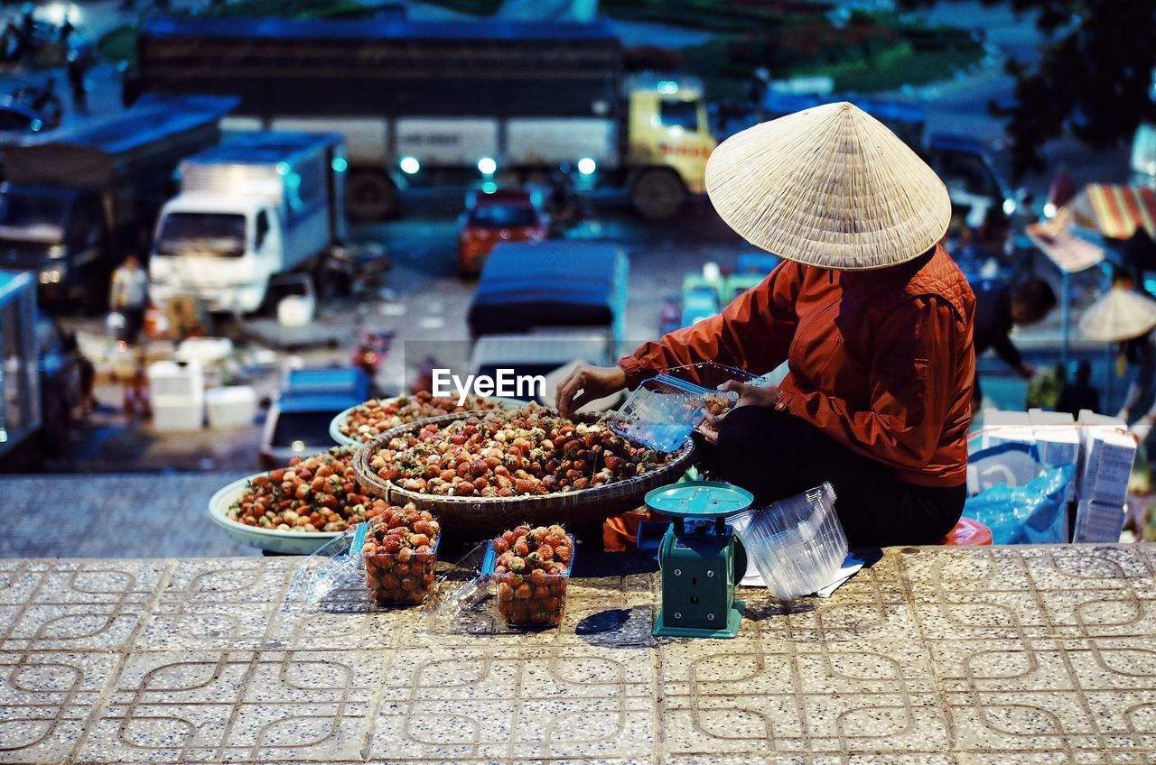 Woman selling fruits on steps at night