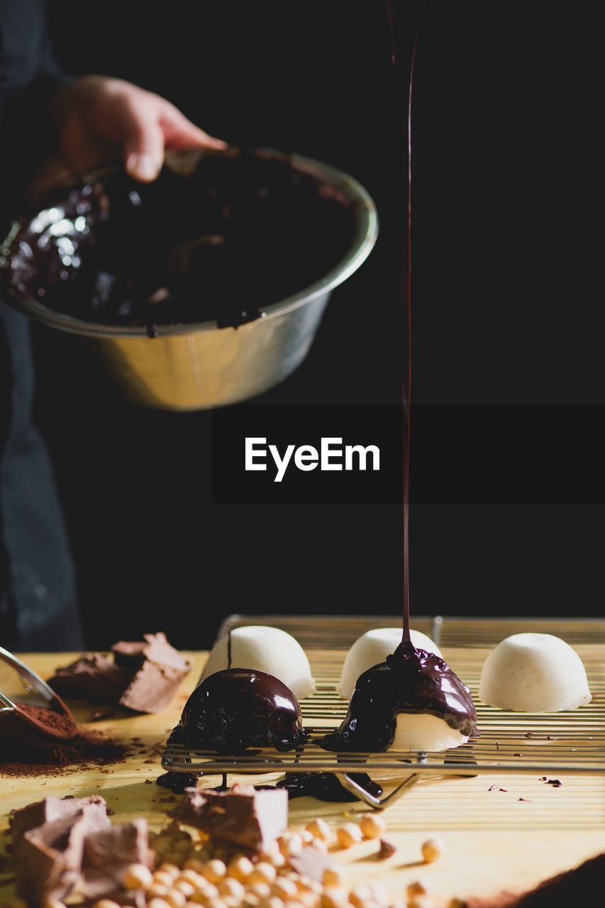 Close-up of chef dripping chocolate onto dessert