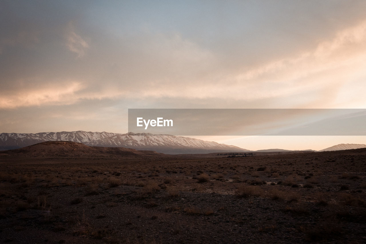 SCENIC VIEW OF ARID LANDSCAPE AGAINST SKY AT SUNSET