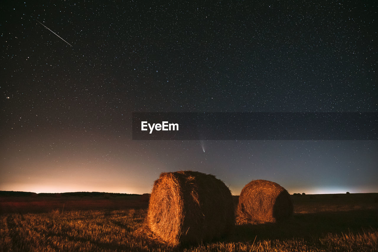 hay bales on field against sky at night