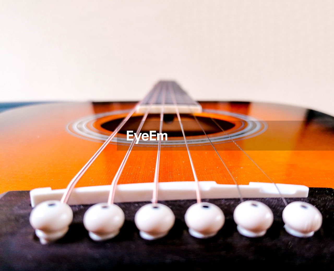 CLOSE-UP OF GUITAR AGAINST GRAY BACKGROUND