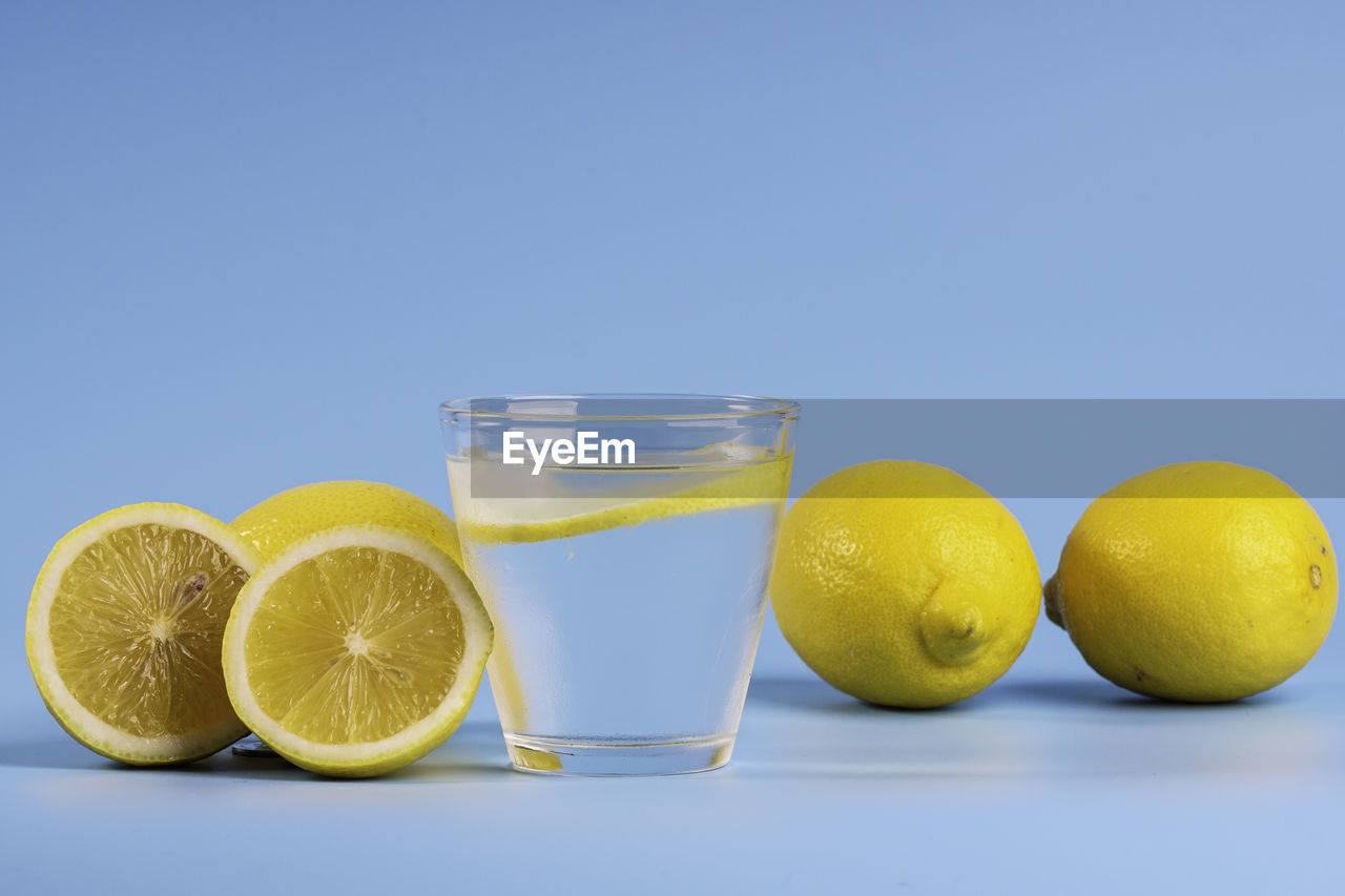 Lemonade with fresh lemons on blue background