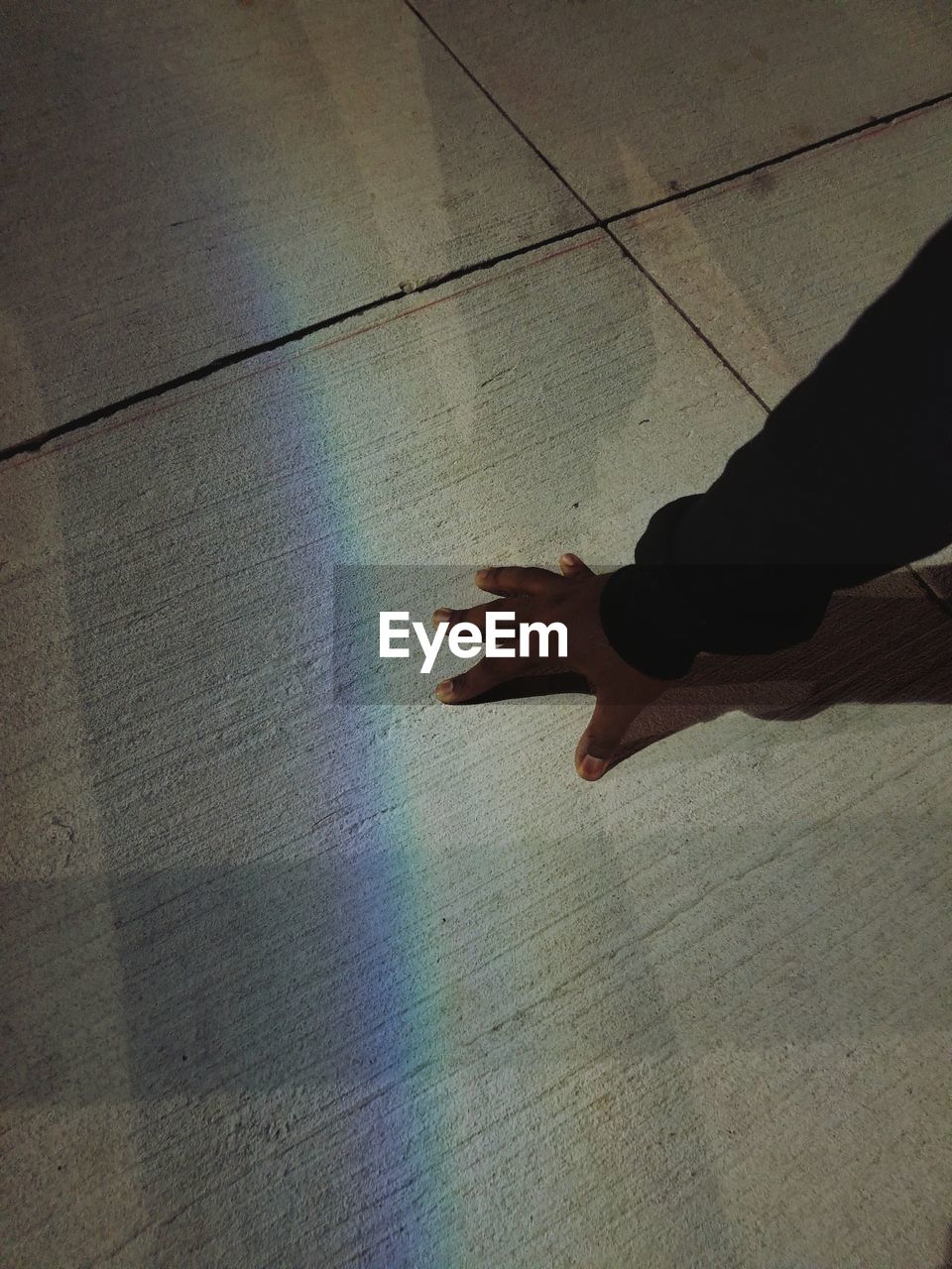 HIGH ANGLE VIEW OF HUMAN HAND ON MULTI COLORED SHADOW