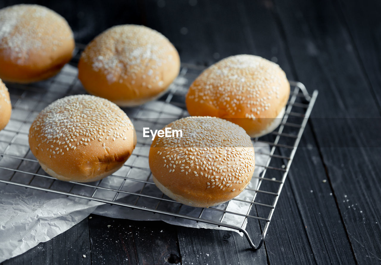 High angle view of tasty buns with sesame on black table.