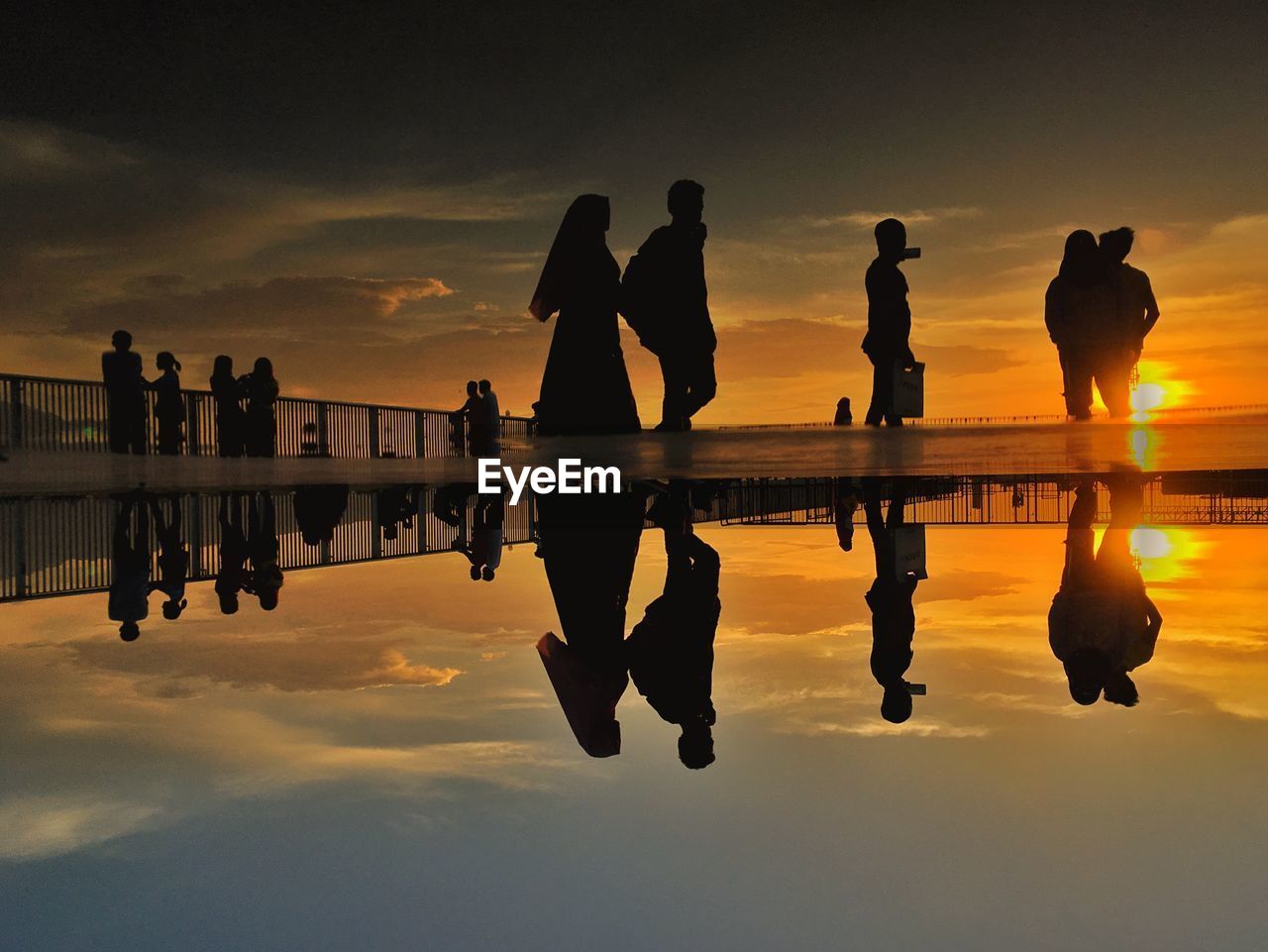 Silhouette people at beach against sky during sunset