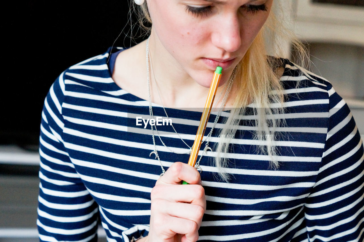 Close-up of thoughtful young woman holding pen