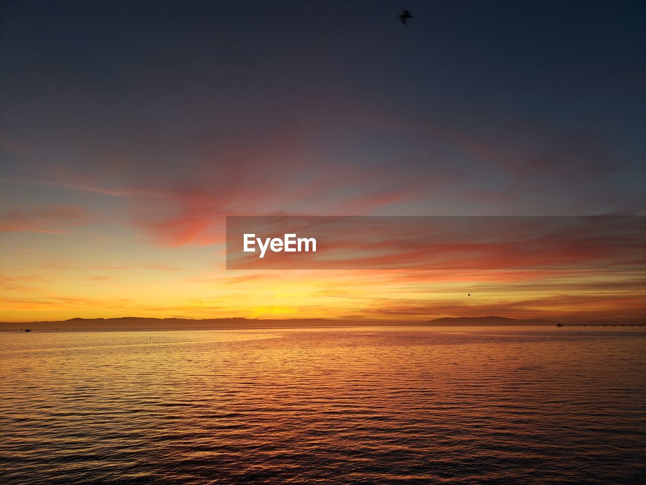 Scenic view of sea against dramatic sky during sunset