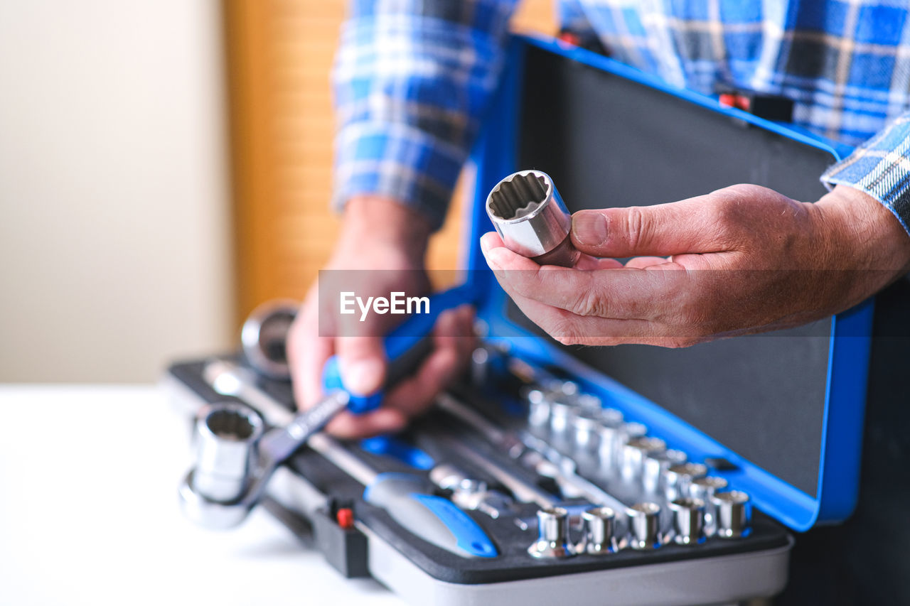 CLOSE-UP OF MAN WORKING ON BLUE MACHINE