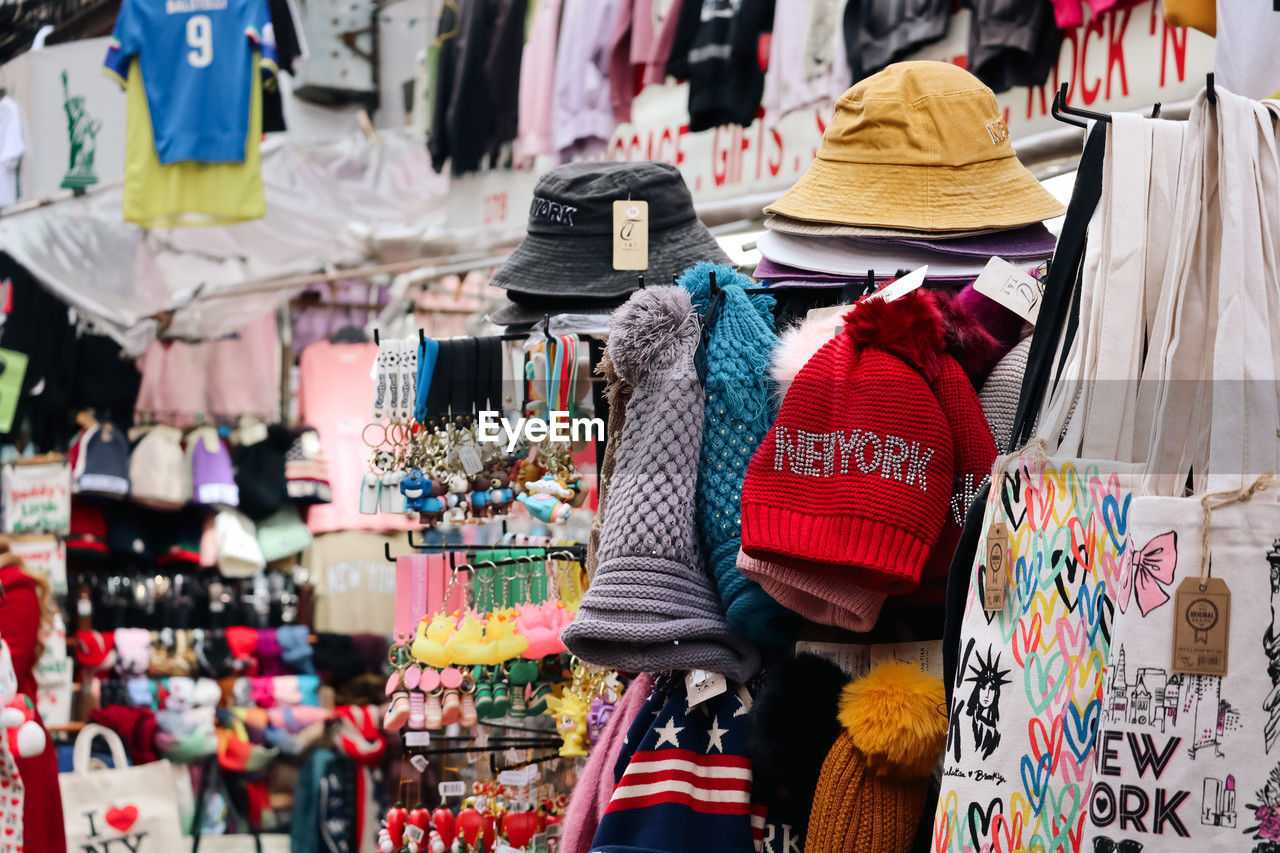 retail, clothing, variation, multi colored, market, store, public space, city, shopping, hanging, fashion, business, business finance and industry, market stall, hat, textile, large group of objects, for sale, fashion accessory, consumerism, retail display, adult, small business, abundance, bazaar, sale, marketplace, day, clothing store, lifestyles, women, holiday, outdoors, flea market, selling