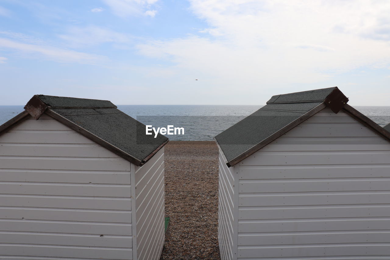 Hut on beach by sea against sky