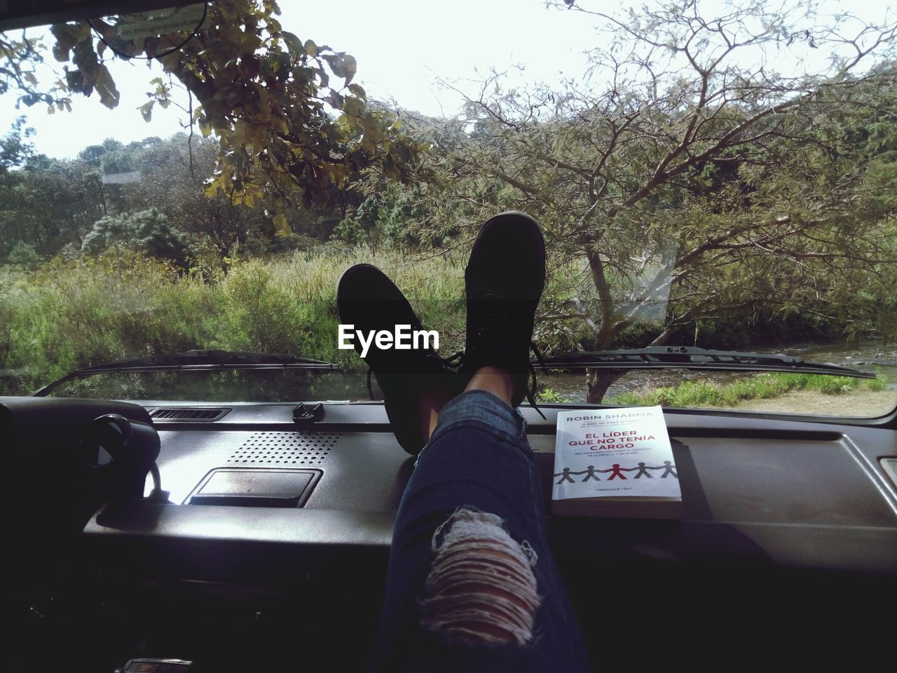 LOW SECTION OF WOMAN BY CAR AGAINST SKY