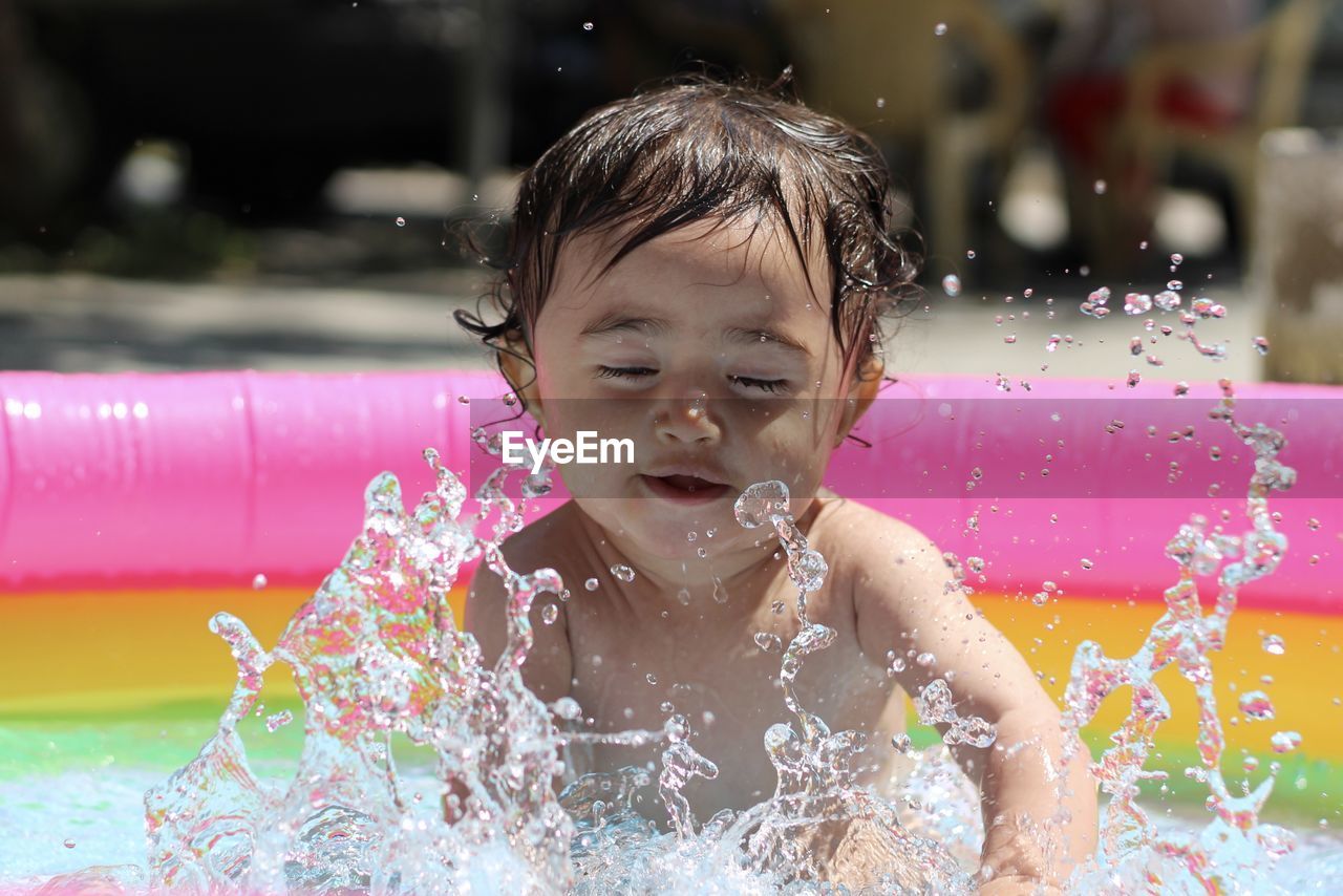 Cute baby splashing water in swimming pool
