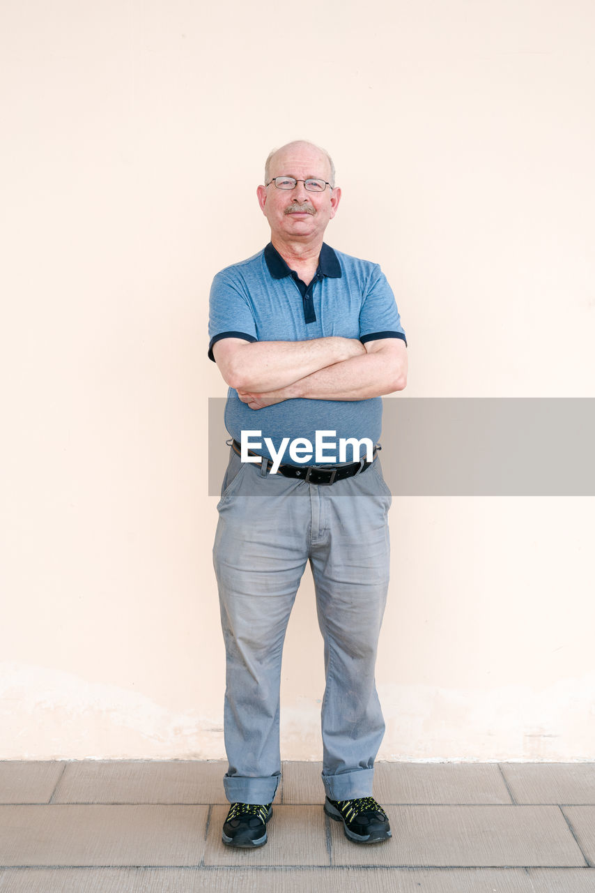 Man with arms crossed standing against wall