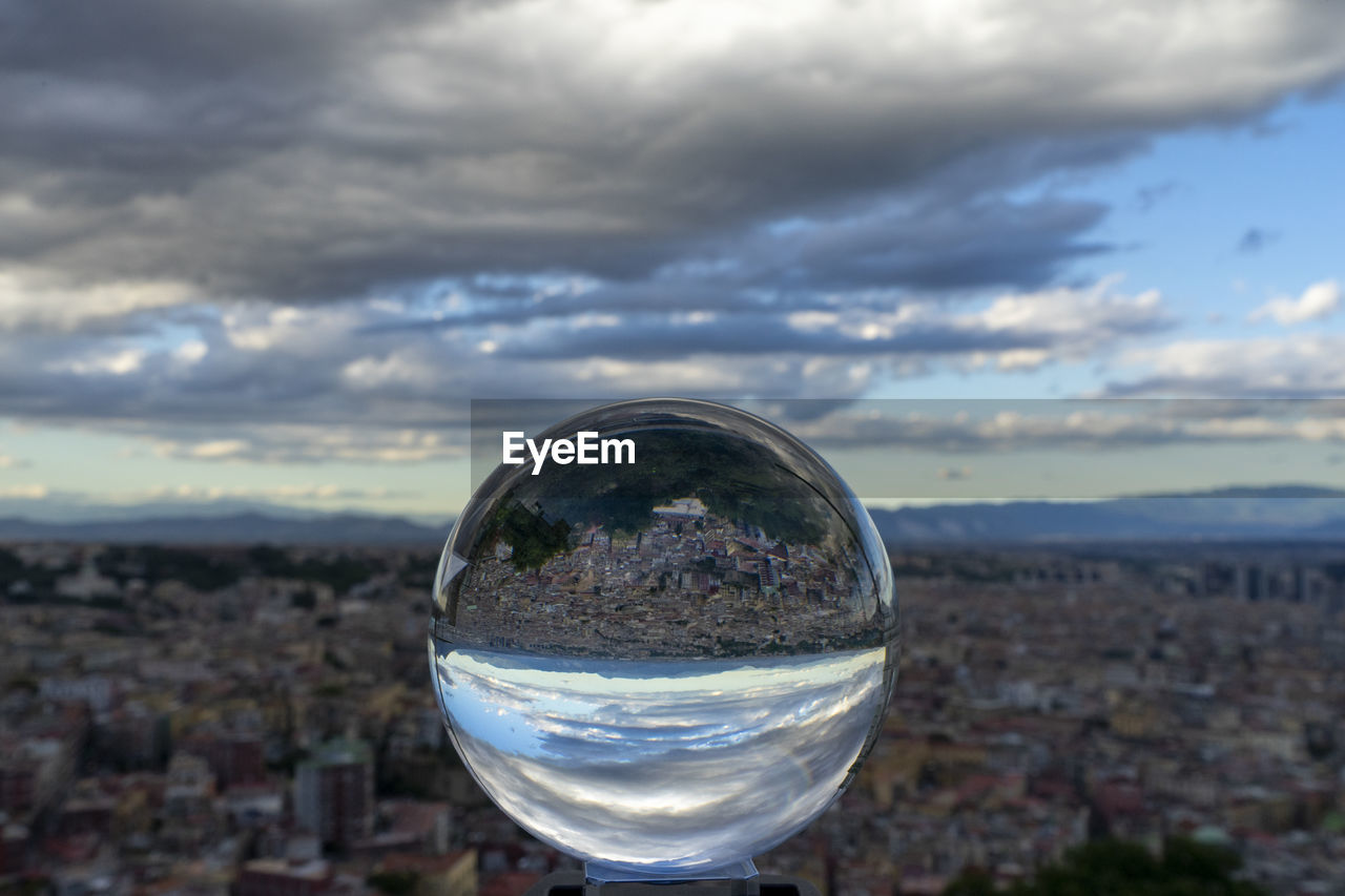 CLOSE-UP OF CRYSTAL BALL IN GLASS AGAINST SKY