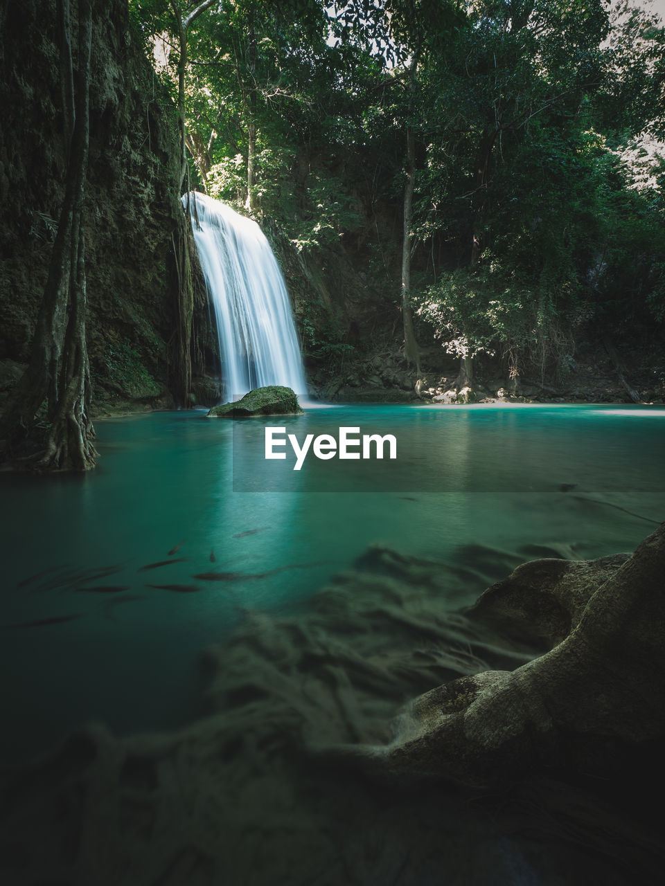 Scenic waterfall with turquoise pond and sunbeam in forest. erawan falls, kanchanaburi, thailand.