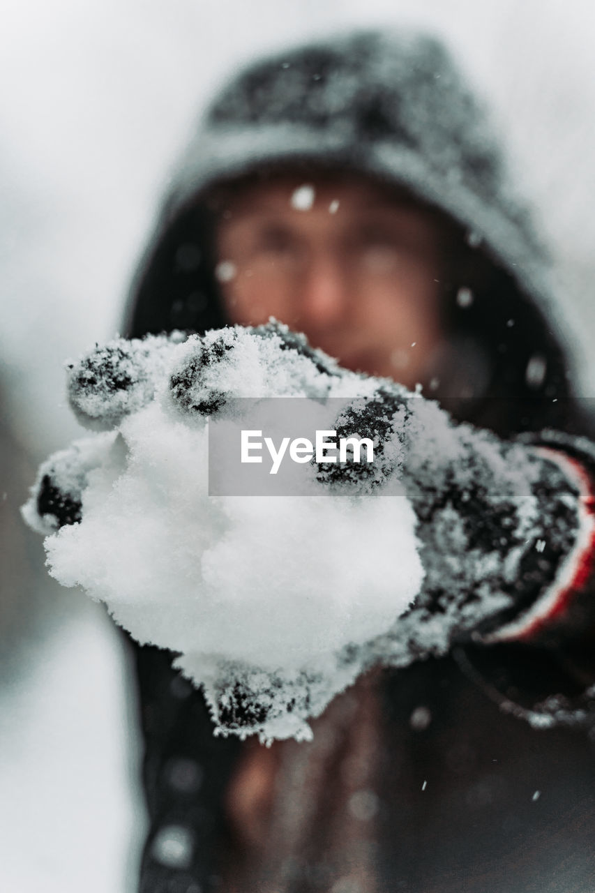 CLOSE-UP PORTRAIT OF SNOW COVERED MAN WITH ICE CREAM