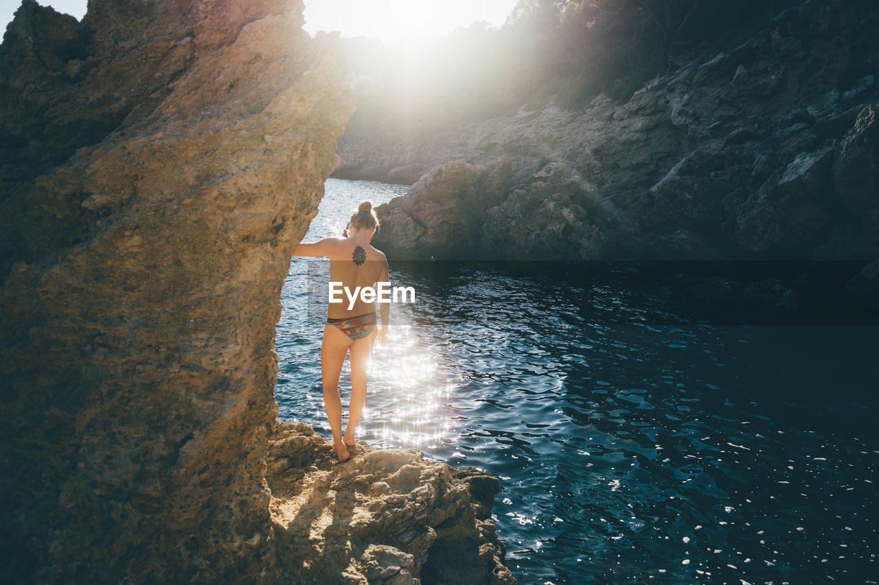 Young woman standing on cliff in summer