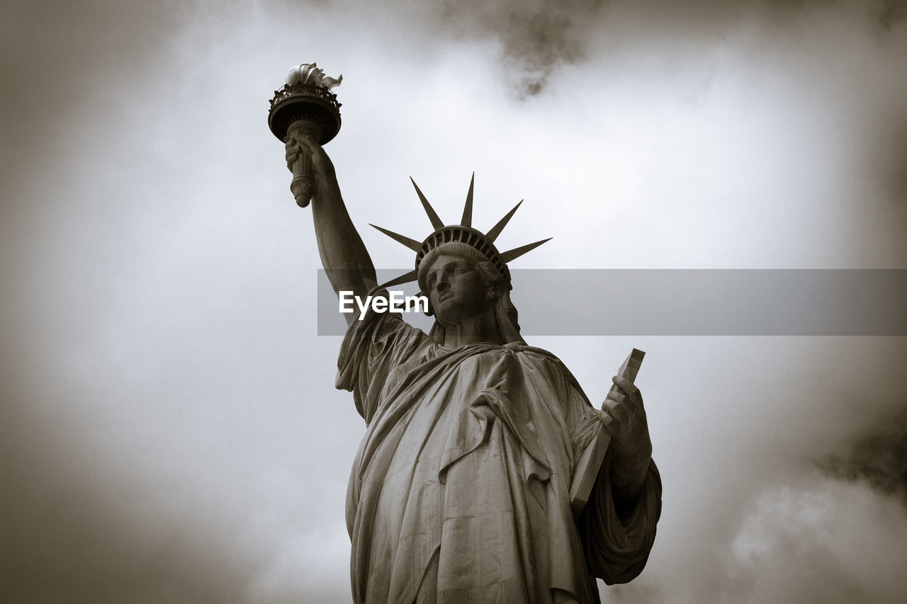 Low angle view of statue of liberty against cloudy sky