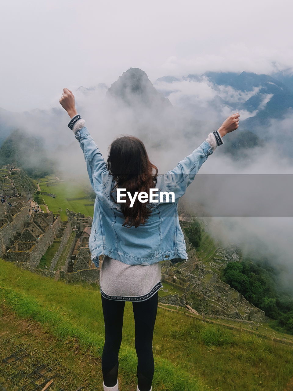 Rear view of woman with arms raised against mountains