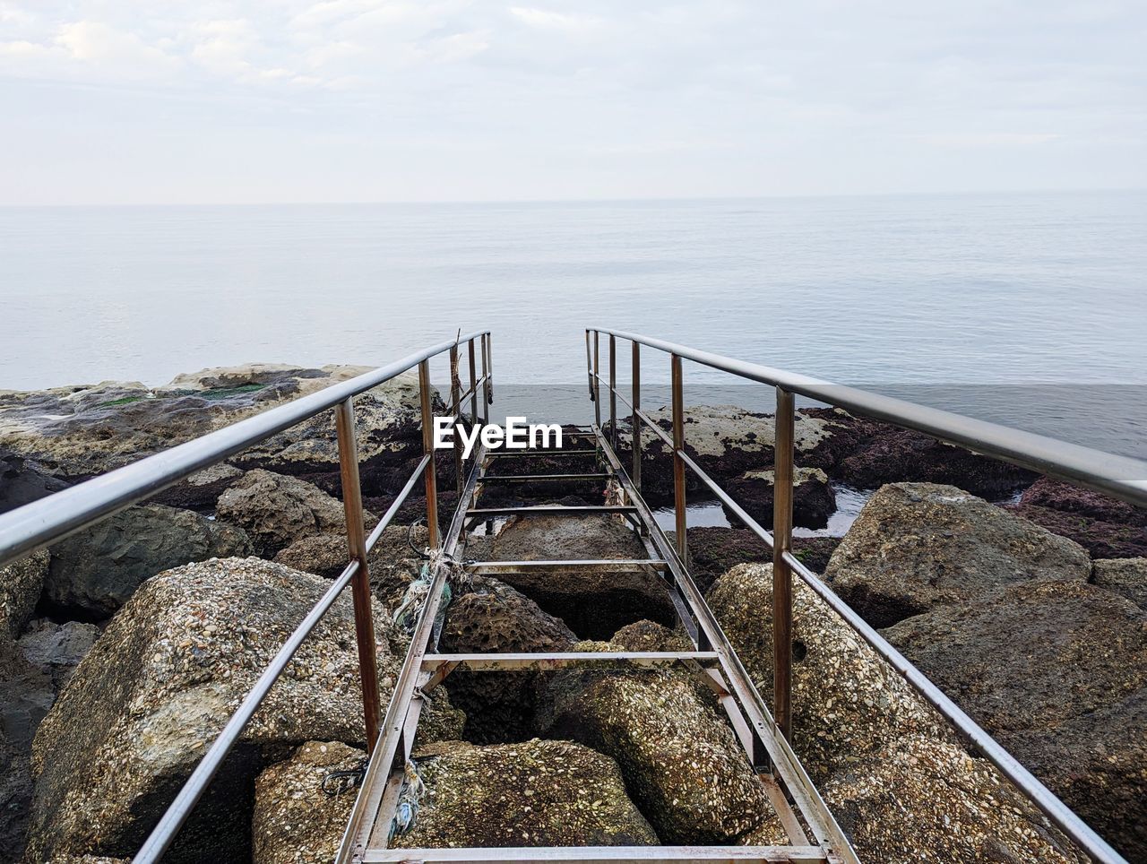 water, sea, horizon over water, horizon, sky, nature, railing, day, beauty in nature, scenics - nature, no people, tranquility, tranquil scene, coast, beach, outdoors, land, high angle view, architecture, shore, non-urban scene, cloud, rock, transportation, metal, idyllic