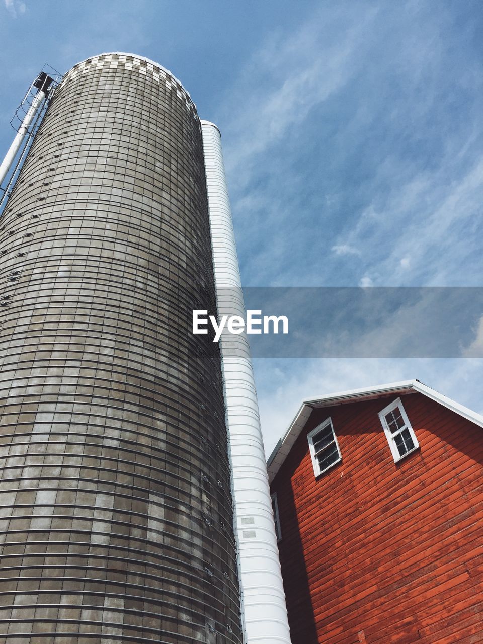 Low angle view of silo and barn against sky