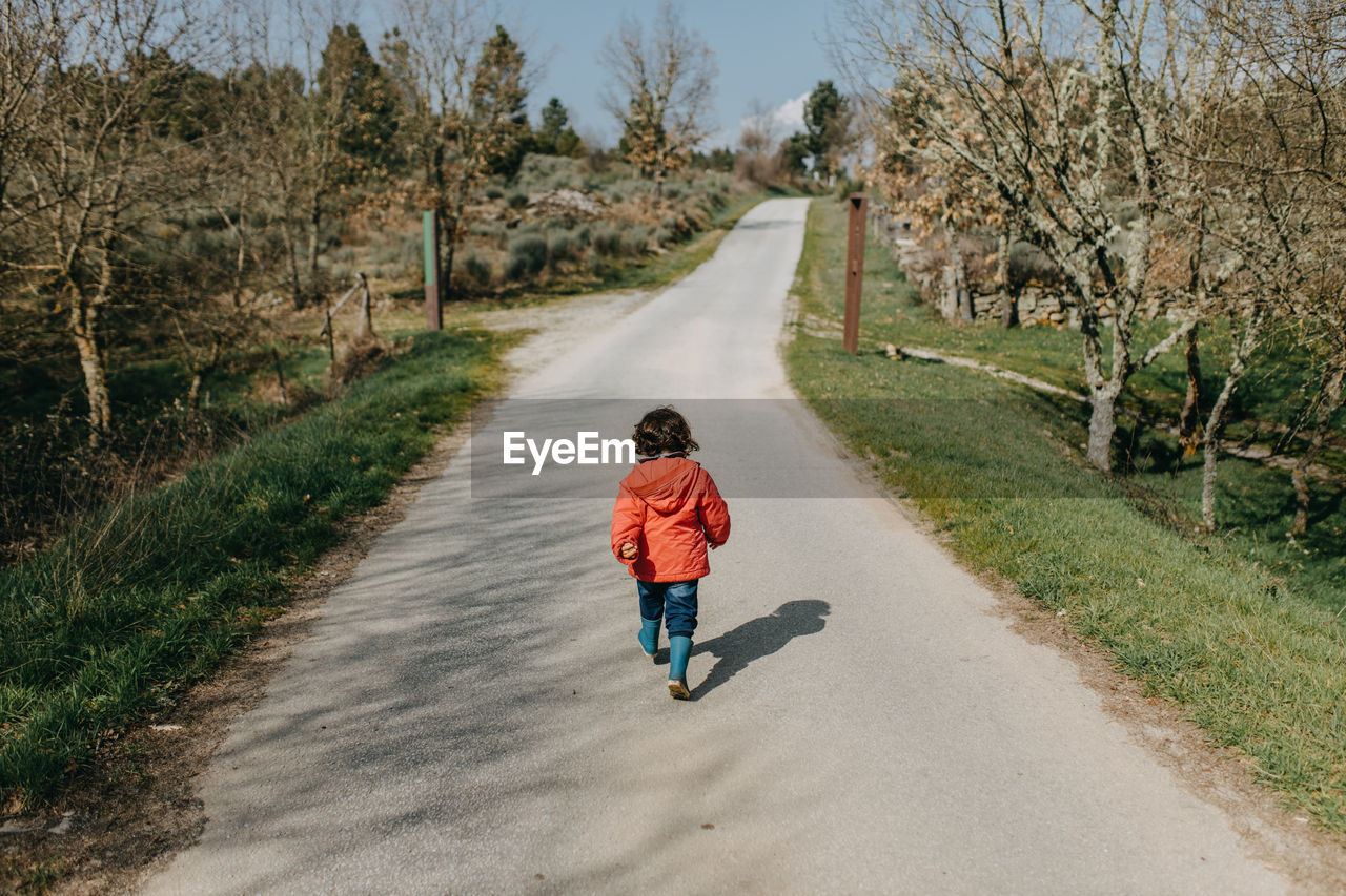 Rear view of chil walking on empty road