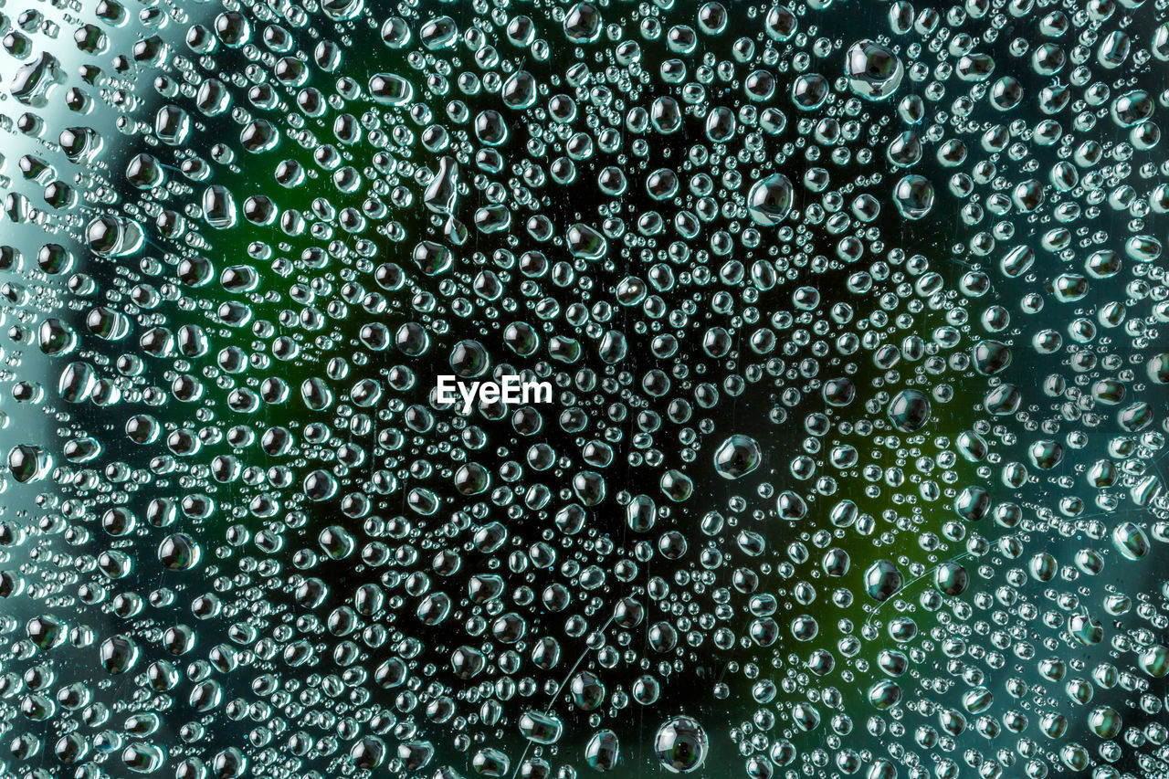 FULL FRAME SHOT OF WET GLASS WITH RAIN DROPS