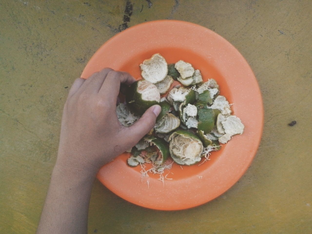 Cropped image of hand holding orange fruit at table