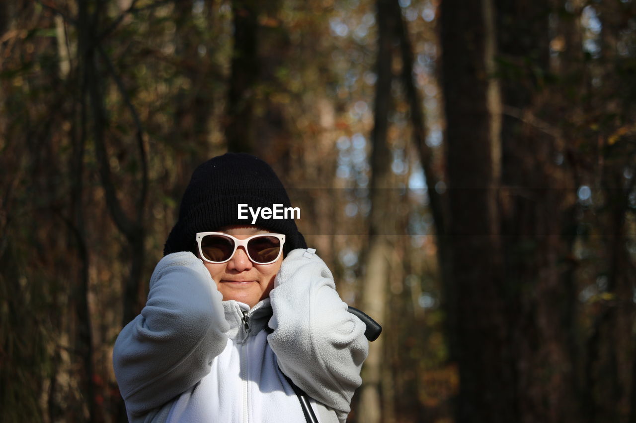 Portrait of woman wearing sunglasses standing in forest