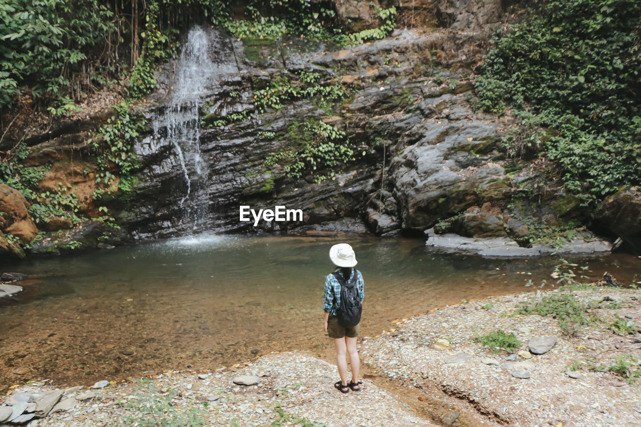 FULL LENGTH OF WOMAN STANDING ON ROCKS IN FOREST