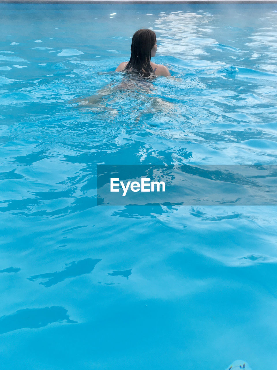 FULL LENGTH REAR VIEW OF WOMAN SWIMMING IN POOL