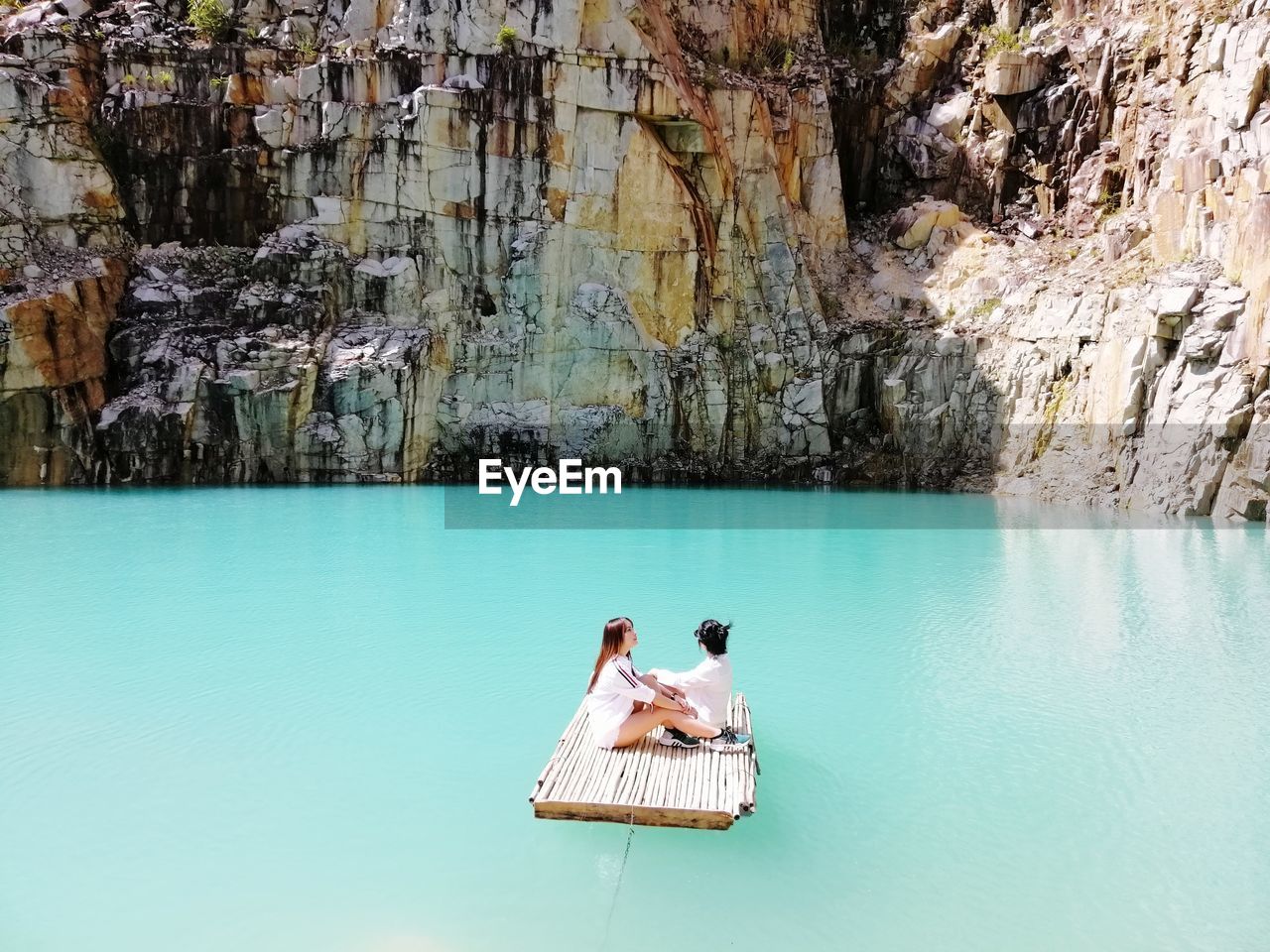 Man sitting on rock by swimming pool