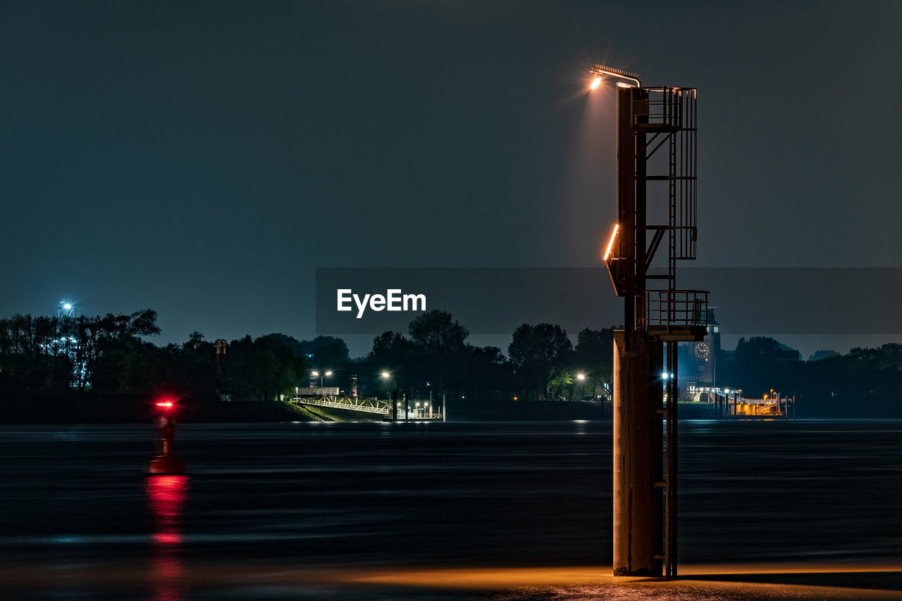 ILLUMINATED STREET LIGHT IN CITY AGAINST SKY AT NIGHT