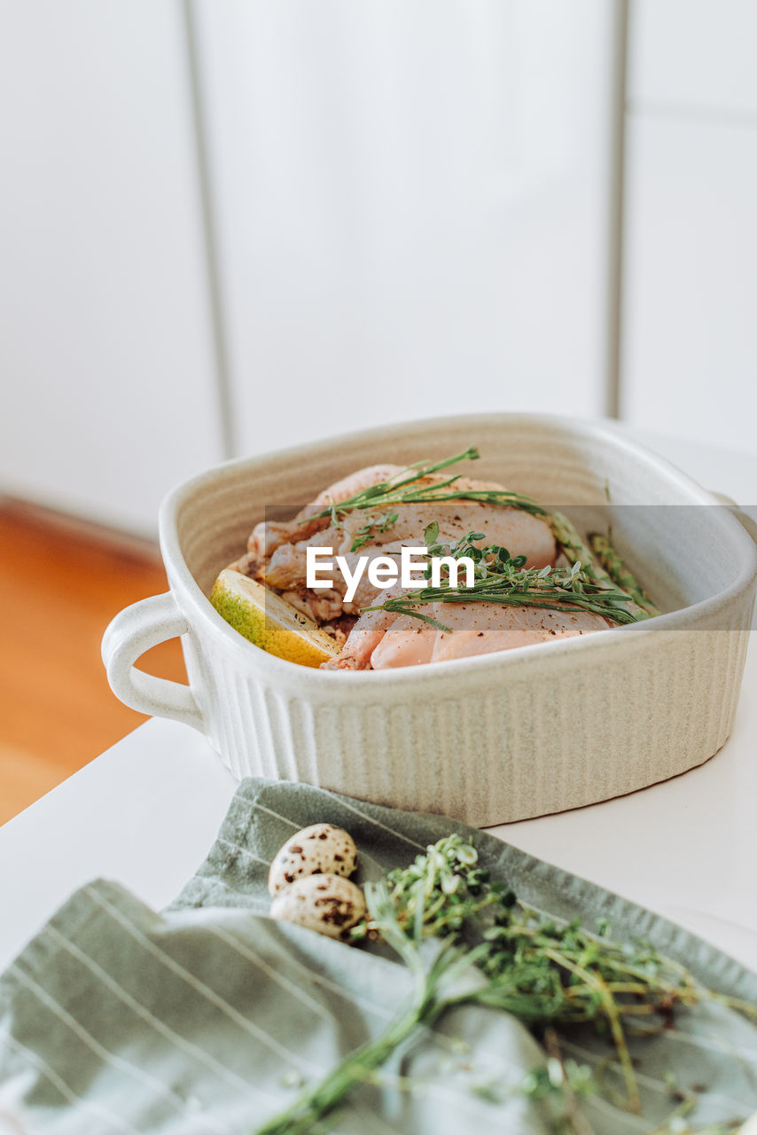 Tray with raw quail or chicken and aromatic herbs before roasting