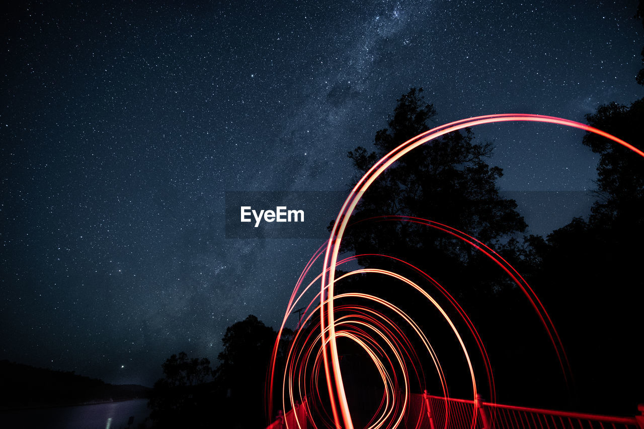 LOW ANGLE VIEW OF ILLUMINATED LIGHT AGAINST SKY AT NIGHT