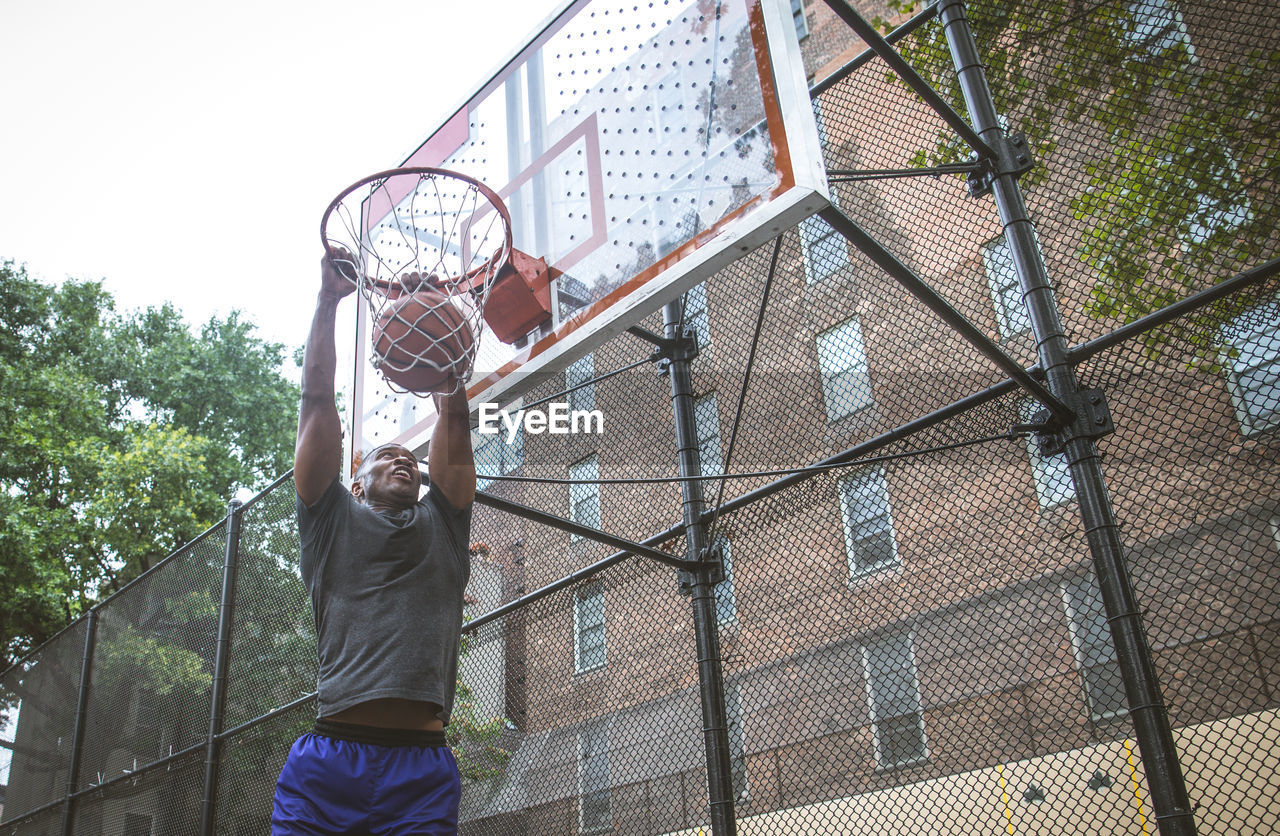 Young man scoring goal at basketball court