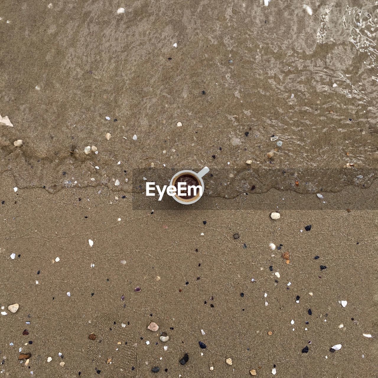 Directly above shot of coffee cup on shore at beach