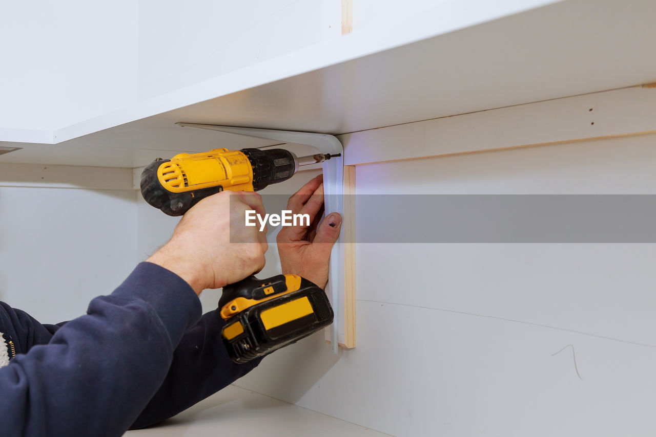 Cropped hand of man working with nail gun at home