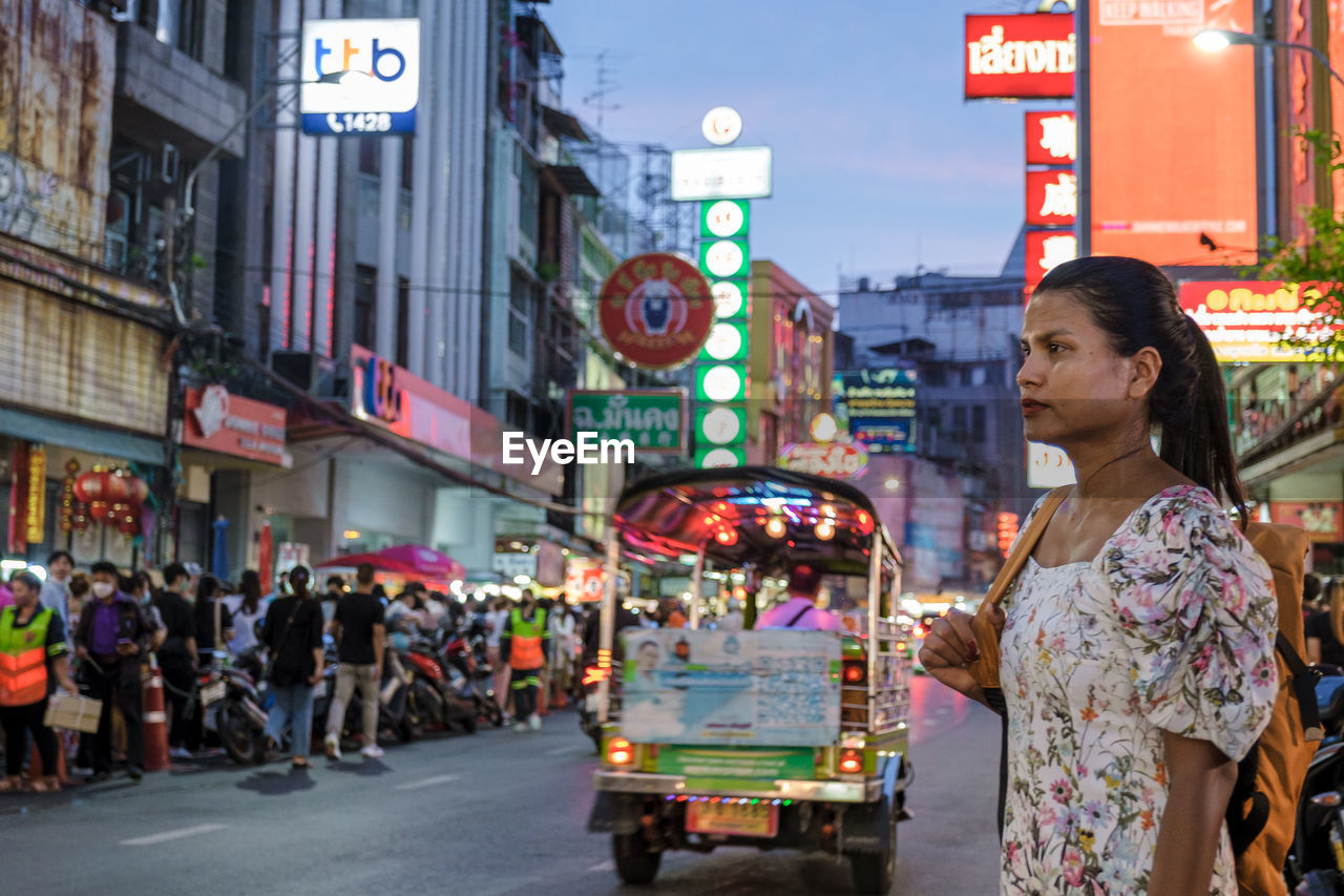 portrait of young woman standing on street in city