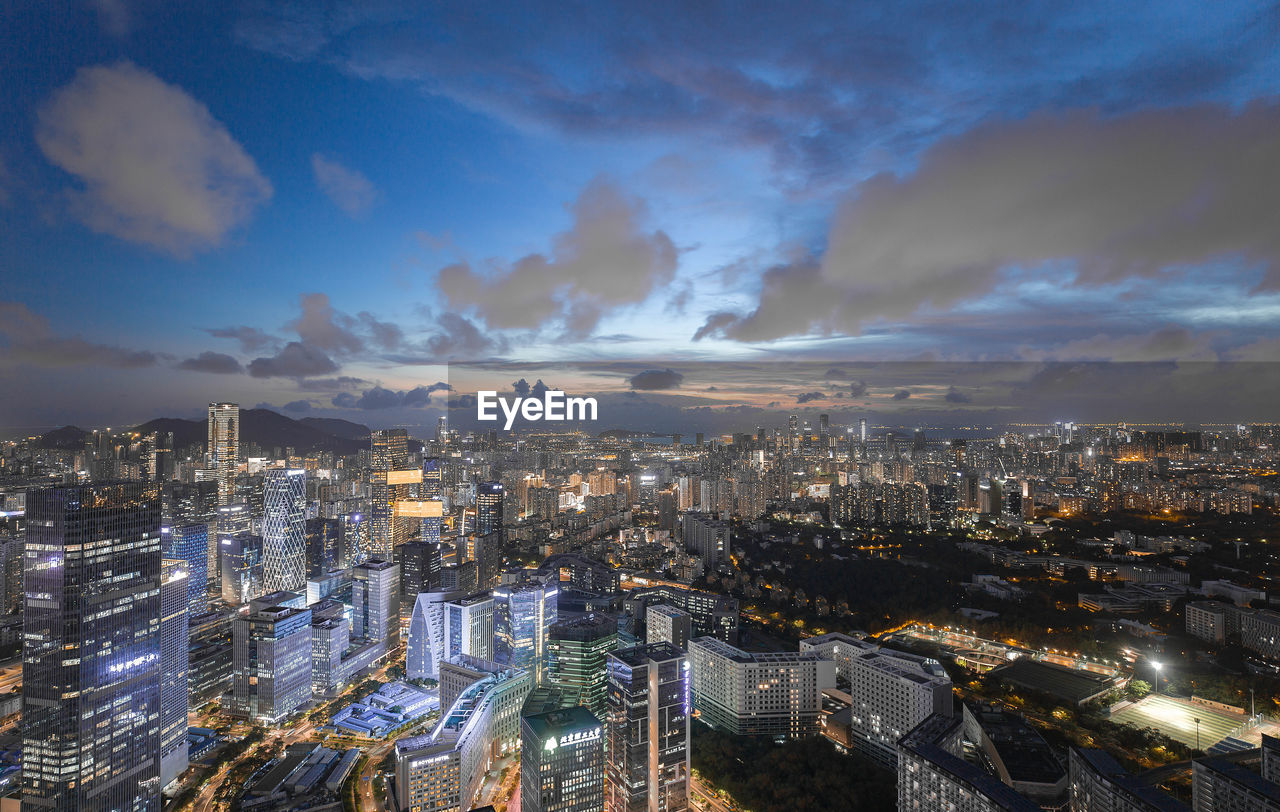 HIGH ANGLE VIEW OF ILLUMINATED BUILDINGS AGAINST SKY