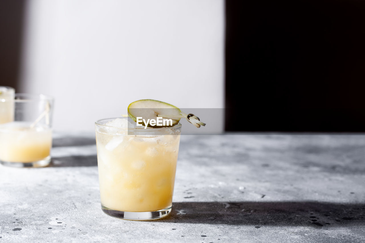 Glass of refreshing pear soda water mocktail on gray concrete background. non alcoholic summer drink