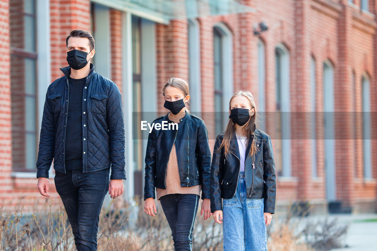 Father and daughters wearing masks while walking outdoors