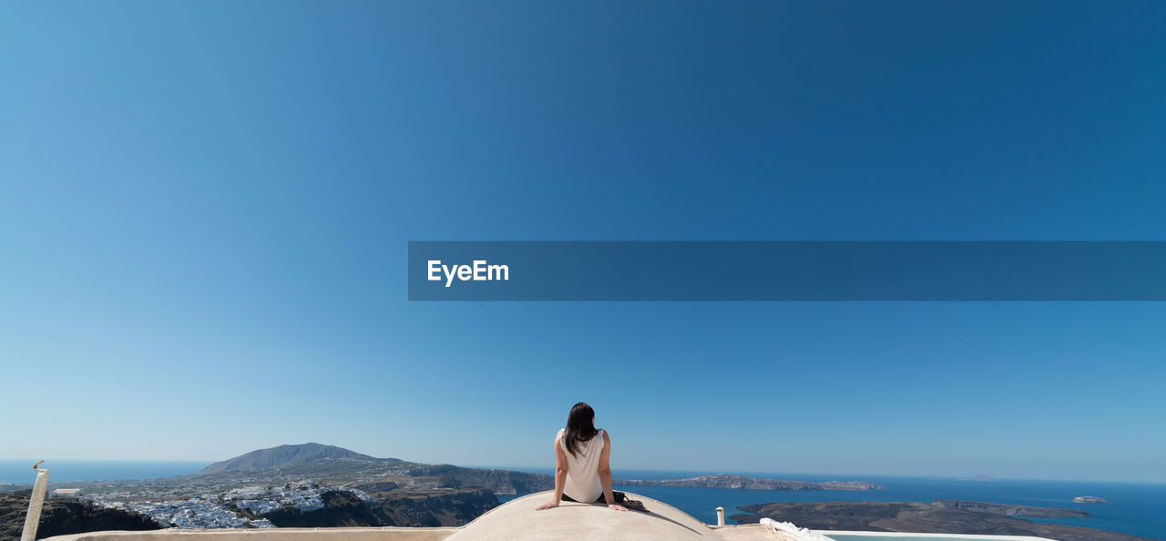REAR VIEW OF WOMAN AGAINST CLEAR SKY