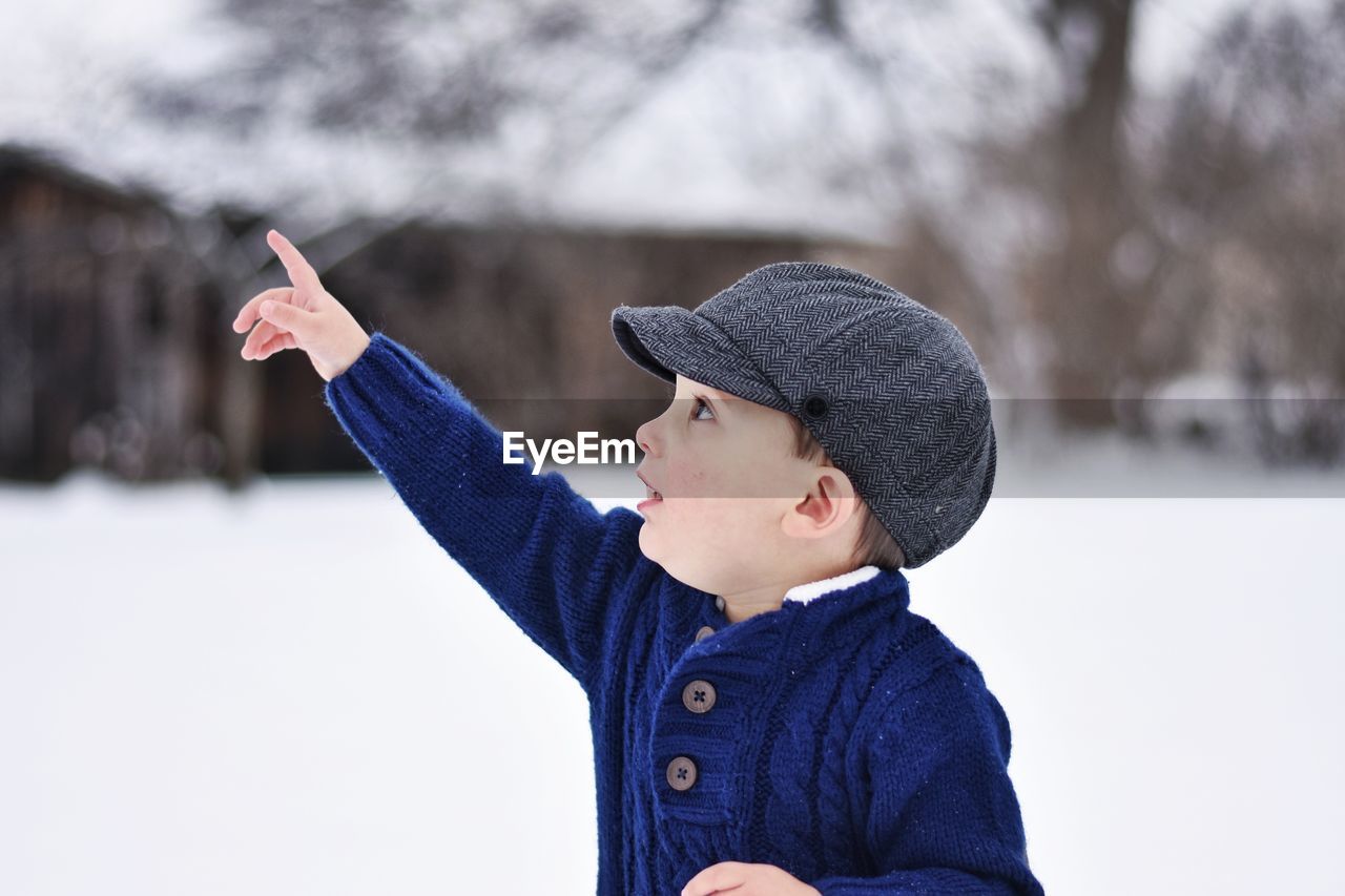 Close-up of cute boy pointing outdoors during winter