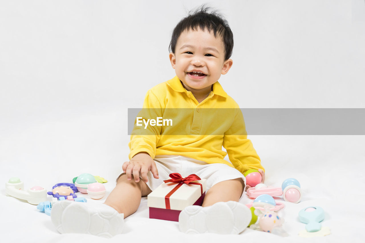 portrait of cute baby boy playing with toy against white background